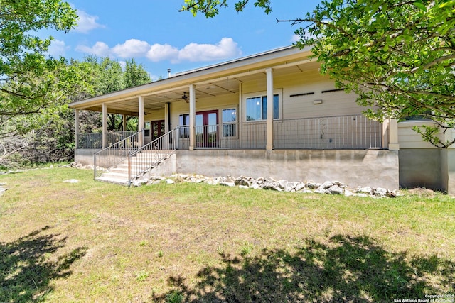 rear view of property featuring stairway, a ceiling fan, and a yard