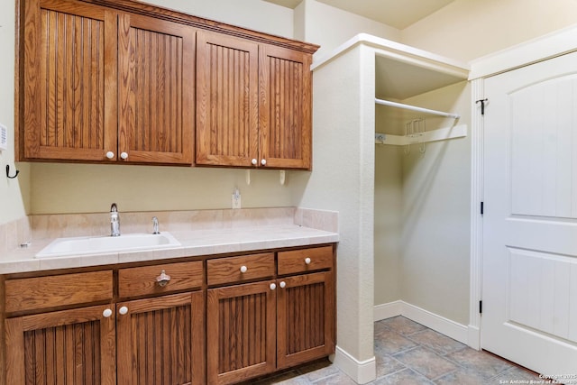 washroom featuring stone tile floors, baseboards, and a sink