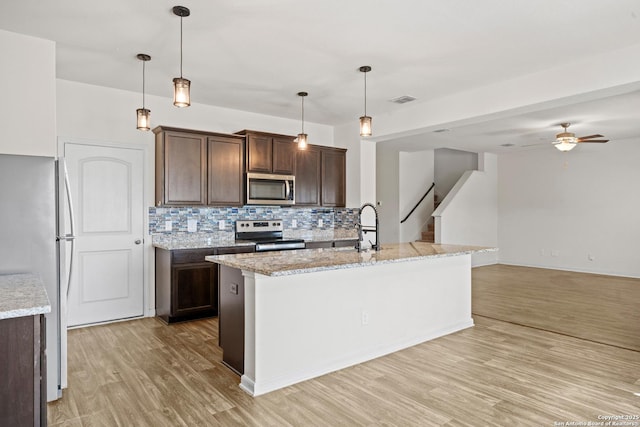 kitchen featuring tasteful backsplash, light wood-style flooring, appliances with stainless steel finishes, a sink, and dark brown cabinetry