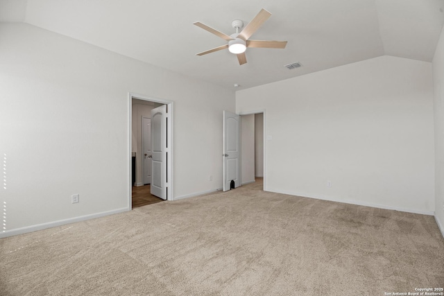 unfurnished bedroom with visible vents, baseboards, lofted ceiling, ensuite bath, and carpet