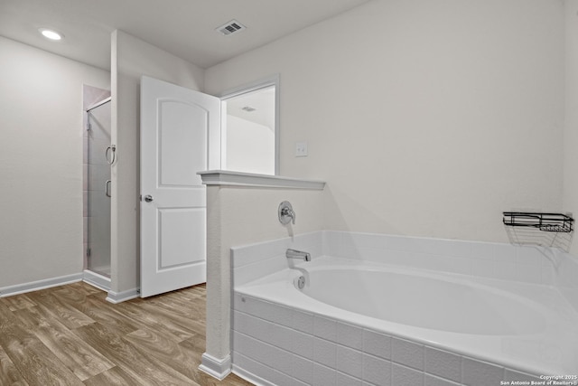 bathroom with a bath, wood finished floors, visible vents, and a shower stall