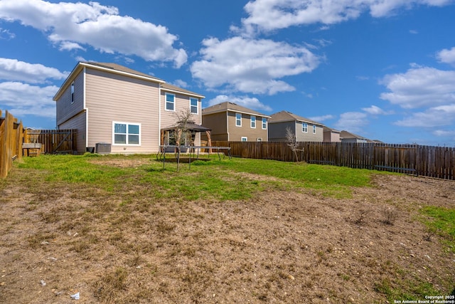 back of house featuring a fenced backyard, central air condition unit, a gazebo, a lawn, and a trampoline