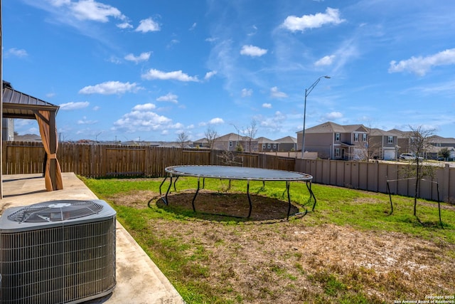 view of yard featuring a fenced backyard, central air condition unit, a gazebo, a residential view, and a trampoline