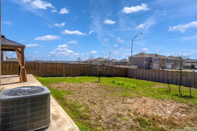 view of yard with a fenced backyard, a residential view, central AC unit, and a gazebo