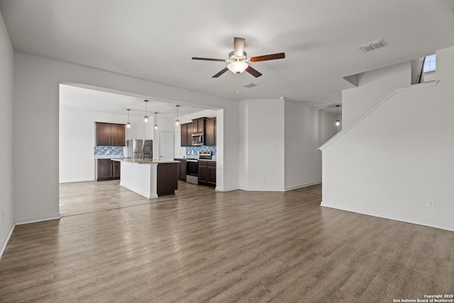 unfurnished living room featuring a ceiling fan, visible vents, and wood finished floors