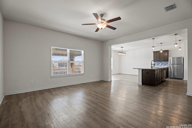 unfurnished living room with baseboards, visible vents, ceiling fan, dark wood-style flooring, and a sink