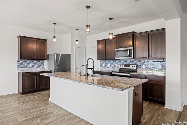 kitchen with appliances with stainless steel finishes, dark brown cabinets, a sink, and wood finished floors