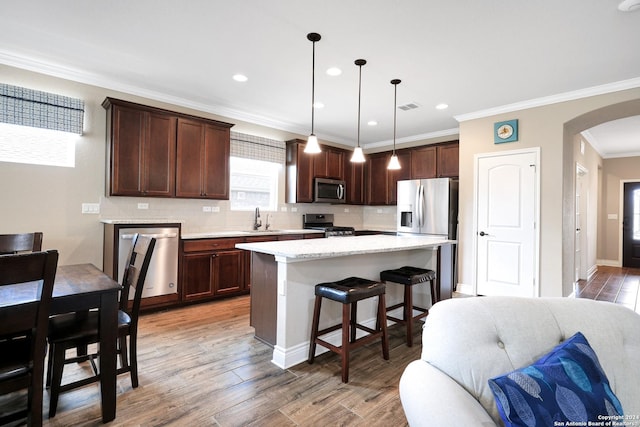 kitchen featuring stainless steel appliances, visible vents, open floor plan, a sink, and light wood-type flooring