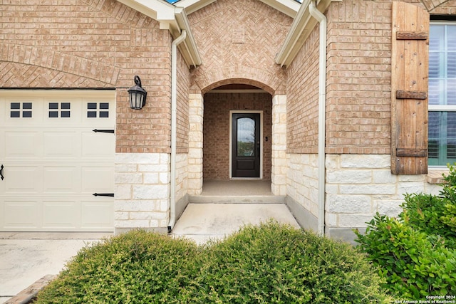 property entrance featuring an attached garage, stone siding, and brick siding