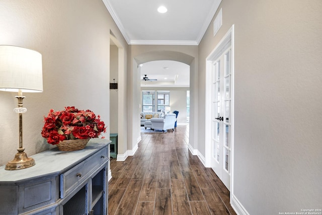 corridor with dark wood-style floors, arched walkways, crown molding, recessed lighting, and baseboards