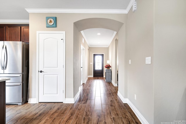 hallway featuring arched walkways, ornamental molding, dark wood finished floors, and baseboards