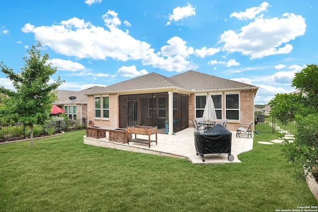 rear view of property with brick siding, a patio, a lawn, a sunroom, and a fenced backyard