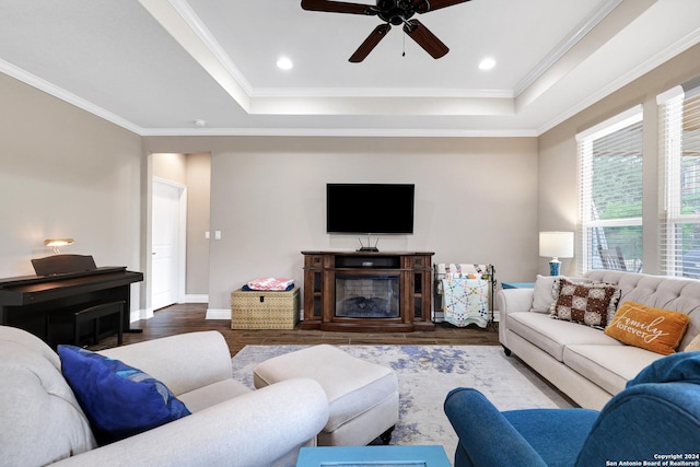 living room featuring crown molding, recessed lighting, a raised ceiling, wood finished floors, and baseboards