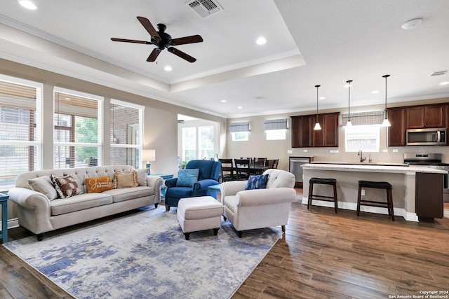 living area featuring visible vents, dark wood finished floors, and a tray ceiling