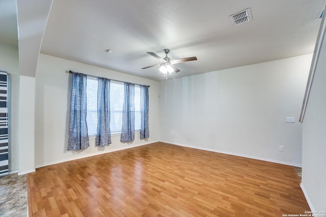 empty room featuring ceiling fan, light wood-type flooring, visible vents, and baseboards