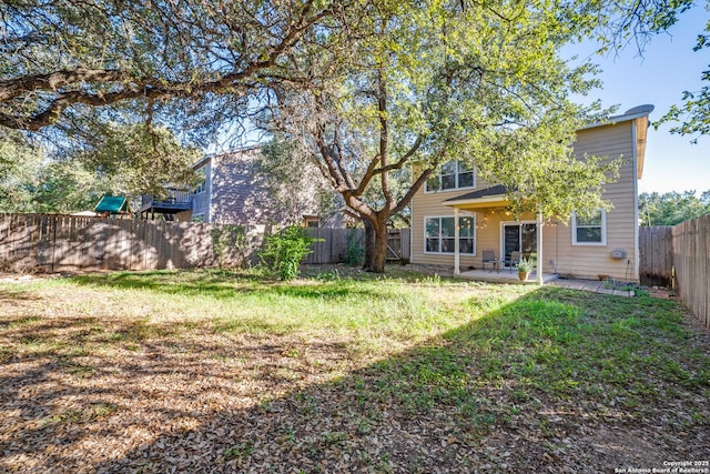 back of property with a fenced backyard, a patio, and a lawn