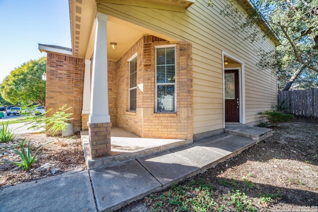 doorway to property with brick siding and fence