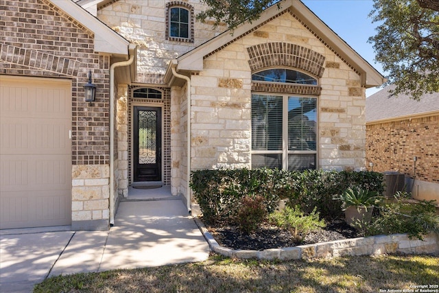 entrance to property with a garage, stone siding, and brick siding