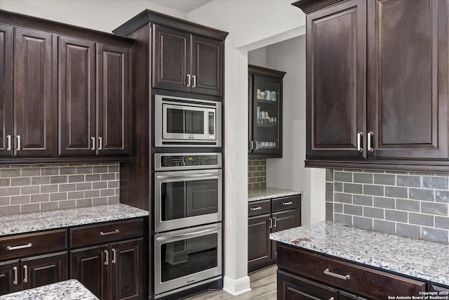 kitchen with dark brown cabinets, appliances with stainless steel finishes, and light stone countertops