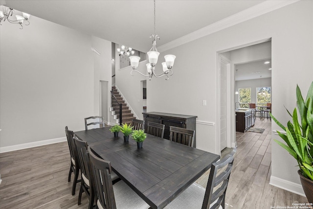 dining area featuring baseboards, light wood-style flooring, stairway, crown molding, and a chandelier