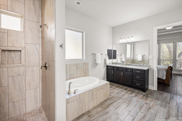 full bathroom with a garden tub, wood finish floors, a tile shower, and vanity