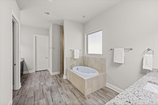 full bathroom with baseboards, visible vents, wood finished floors, vanity, and a bath