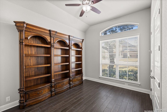 spare room featuring lofted ceiling, dark wood-style flooring, a ceiling fan, and baseboards