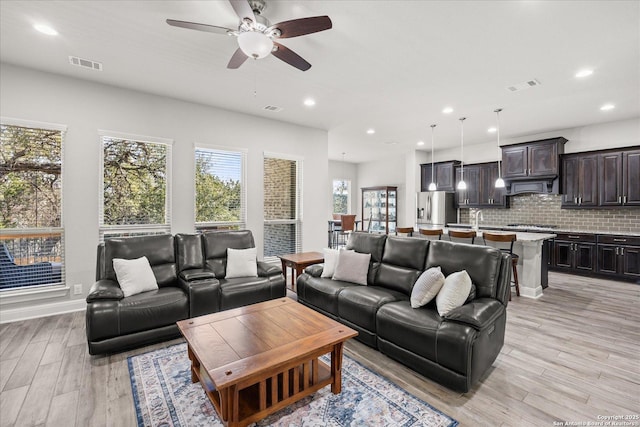 living room with light wood-style flooring, visible vents, and recessed lighting