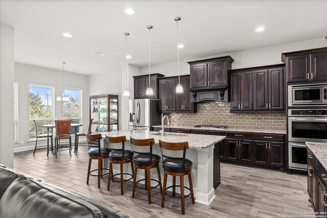 kitchen featuring appliances with stainless steel finishes, a kitchen breakfast bar, backsplash, pendant lighting, and a sink