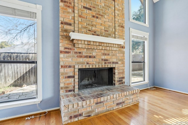 interior details featuring a brick fireplace, baseboards, and wood finished floors