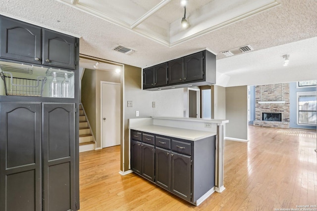 kitchen with light wood-style floors, visible vents, light countertops, and a textured ceiling