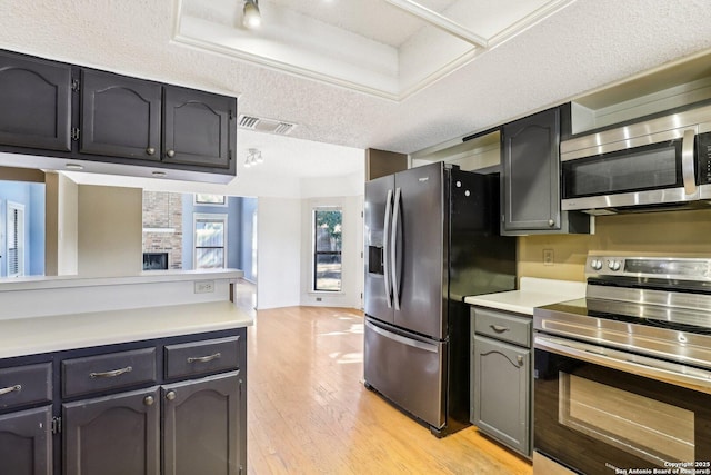 kitchen with visible vents, appliances with stainless steel finishes, light countertops, a textured ceiling, and light wood-type flooring