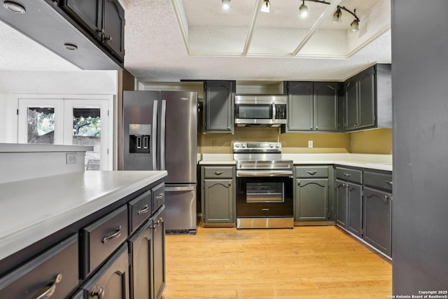 kitchen with light wood finished floors, rail lighting, light countertops, appliances with stainless steel finishes, and a textured ceiling