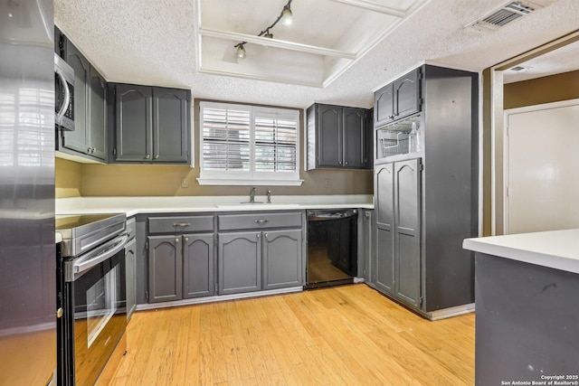 kitchen featuring stainless steel appliances, a sink, visible vents, light wood-style floors, and light countertops