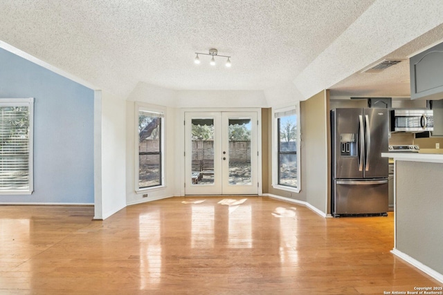 interior space with french doors, visible vents, light wood-style flooring, and a textured ceiling