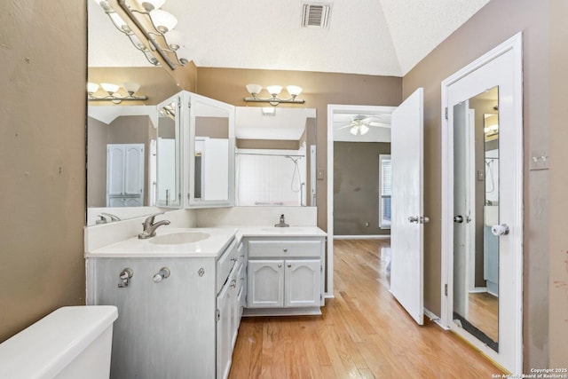 full bath featuring visible vents, toilet, vaulted ceiling, vanity, and wood finished floors