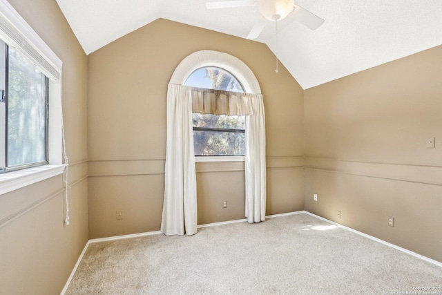 carpeted spare room featuring a ceiling fan, lofted ceiling, and baseboards