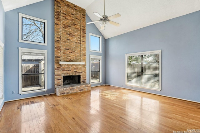 unfurnished living room with a brick fireplace, ceiling fan, high vaulted ceiling, and hardwood / wood-style floors