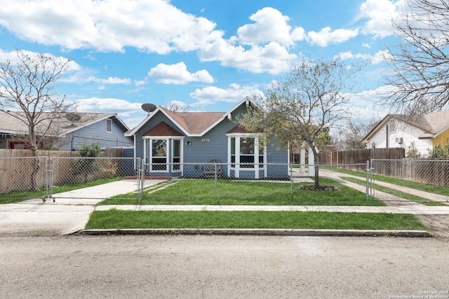 bungalow-style home featuring a fenced front yard, a front yard, and driveway