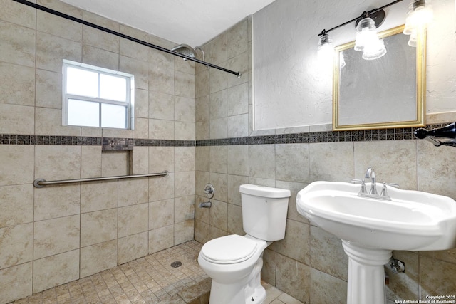 full bath featuring wainscoting, a tile shower, toilet, and tile walls