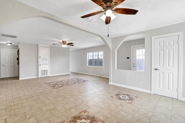 interior space featuring a ceiling fan, arched walkways, visible vents, and a textured ceiling