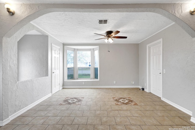 interior space with visible vents, arched walkways, a textured ceiling, and a textured wall