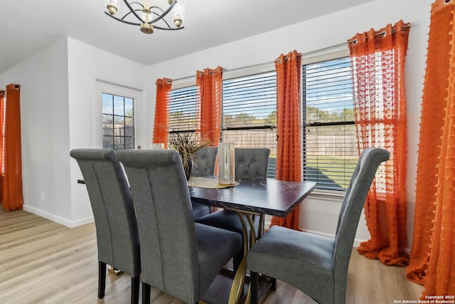 dining area featuring light wood-style flooring, a chandelier, and baseboards