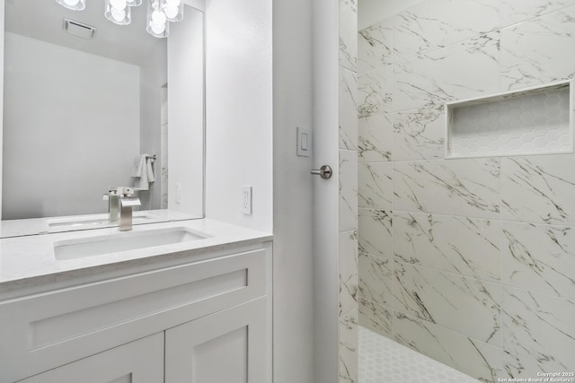 full bath with visible vents, a tile shower, and vanity