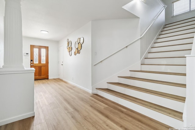 foyer entrance featuring stairway, wood finished floors, decorative columns, and baseboards