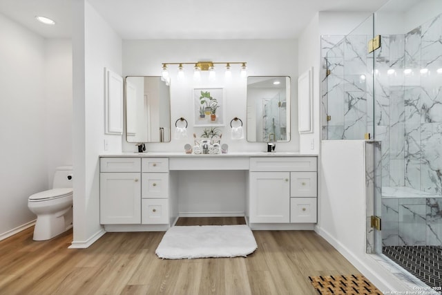 full bathroom featuring toilet, a marble finish shower, a sink, and wood finished floors