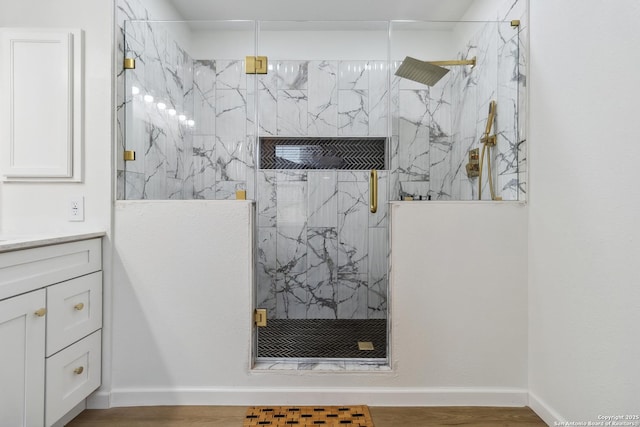 full bath featuring vanity, a marble finish shower, and wood finished floors