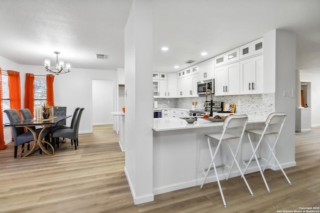 kitchen with stainless steel appliances, decorative backsplash, light countertops, and light wood-style floors