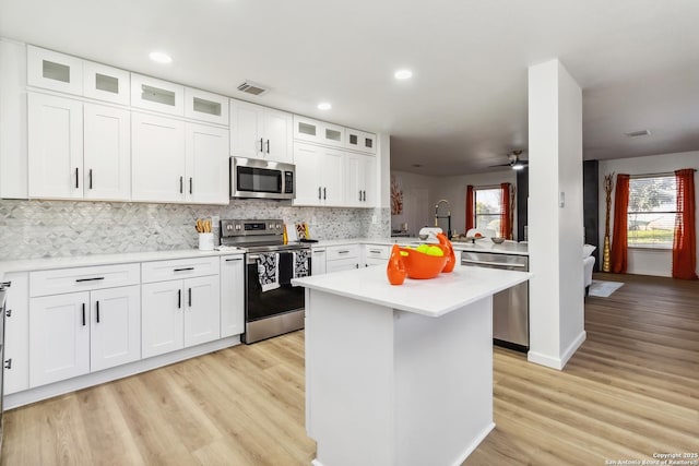 kitchen with stainless steel appliances, light countertops, visible vents, decorative backsplash, and light wood-style floors