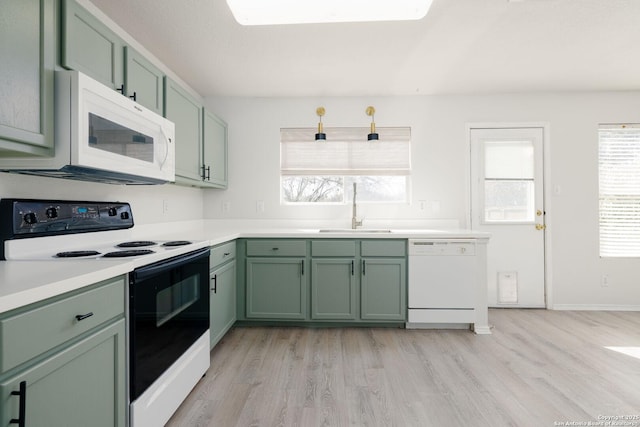 kitchen with light countertops, light wood-style floors, a sink, white appliances, and green cabinetry